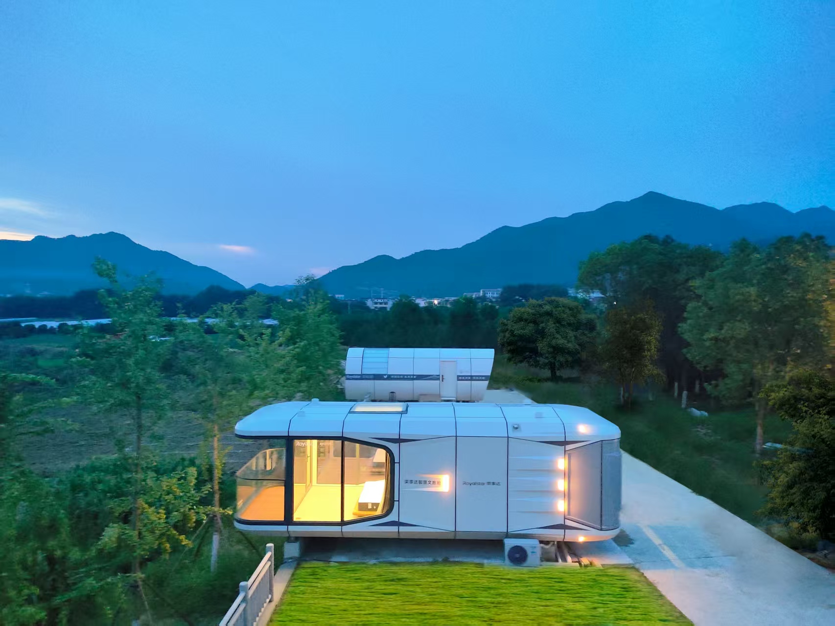 Space Capsule Pod outdoor display scene - glamping in nature with mountain views at dusk